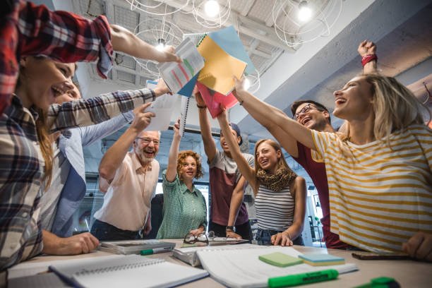 Low angle view of happy university students and their teacher united their textbooks at campus.